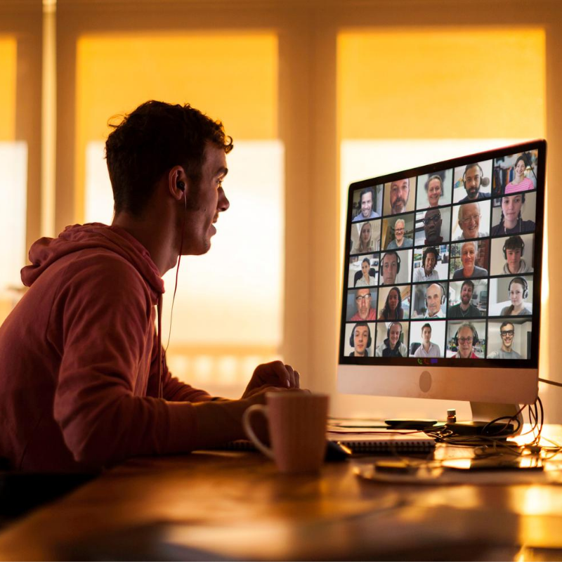 Young man in red hoodie working from home on a video conference call with colleagues